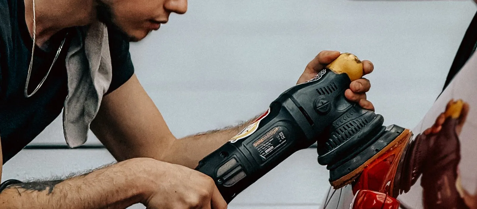 A detailer machine polishing a car, auto detailing web design by Designs by Delia