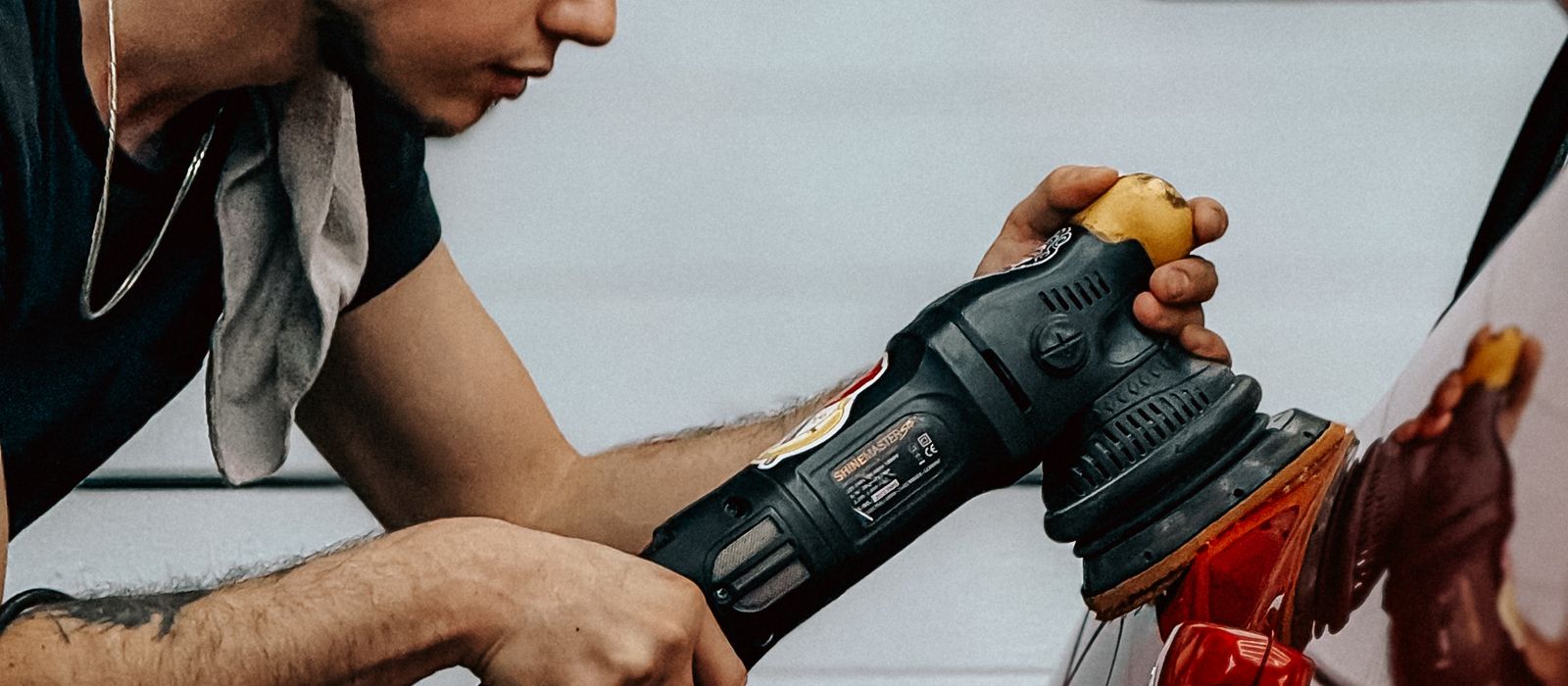A detailer machine polishing a car, auto detailing web design by Designs by Delia
