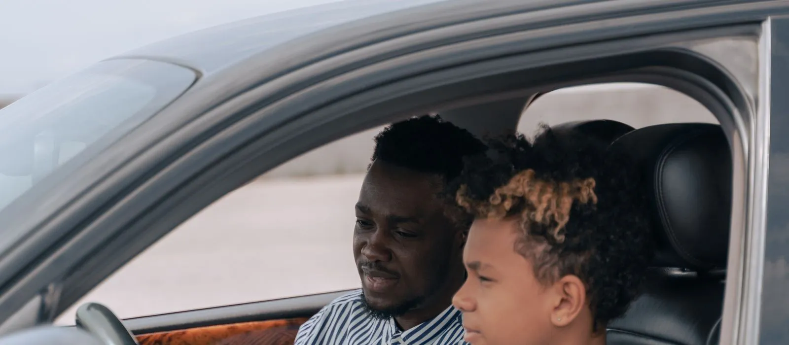 A driving instructor teaching a student behind the wheel, driving school web design by Designs by Delia