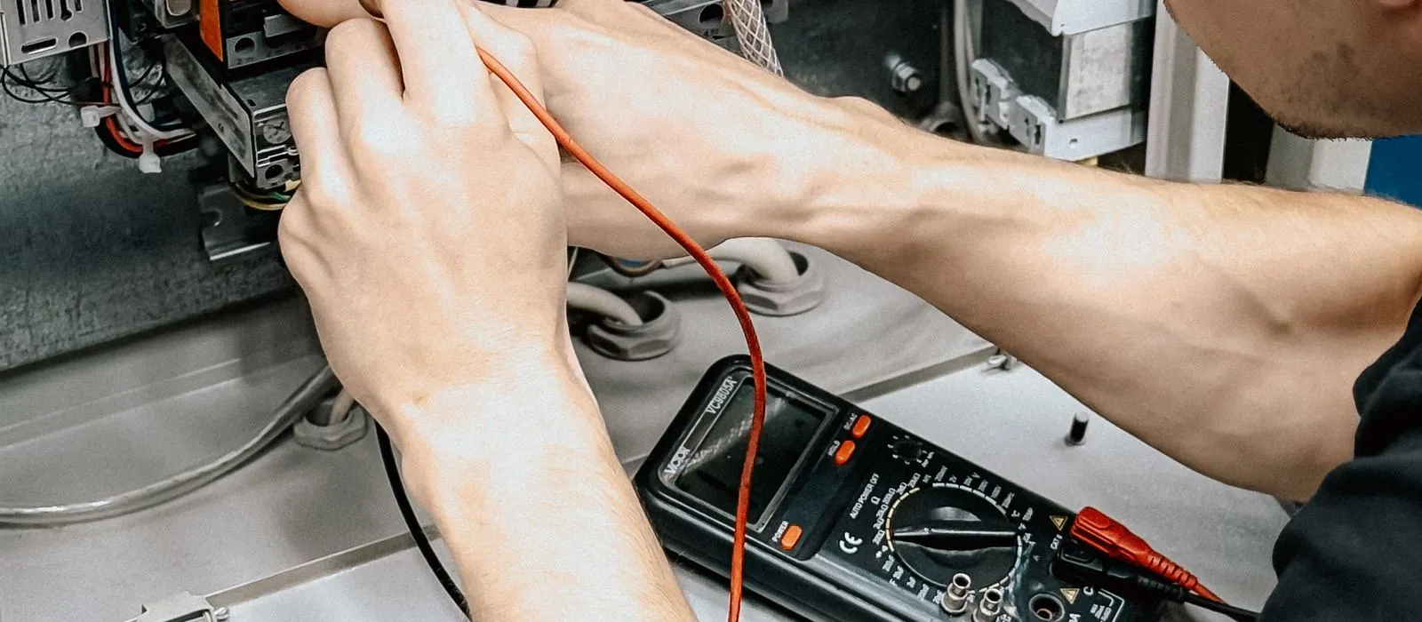 An electrician testing wiring with a multimeter, electrician web design by Designs by Delia