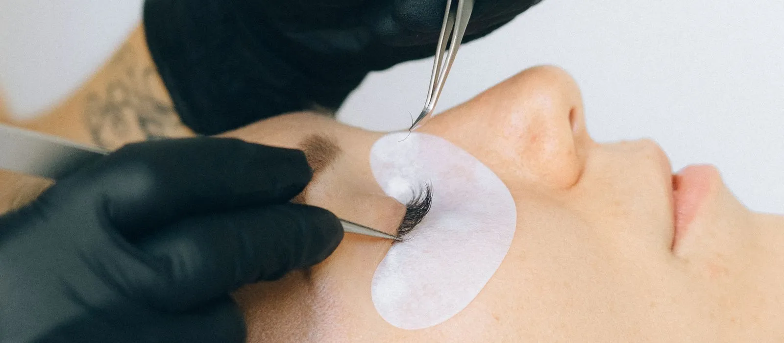 A lash technician applying eyelash extensions to a client, lash studio web design by Designs by Delia