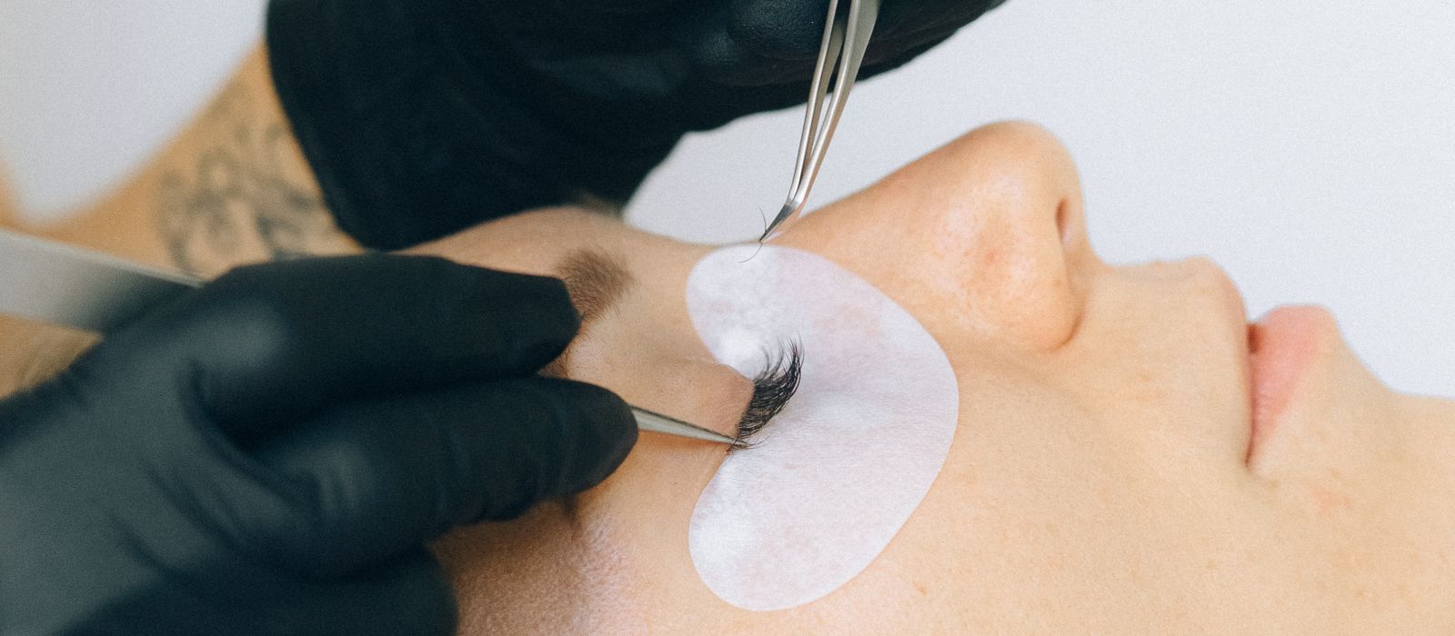 A lash technician applying eyelash extensions to a client, lash studio web design by Designs by Delia