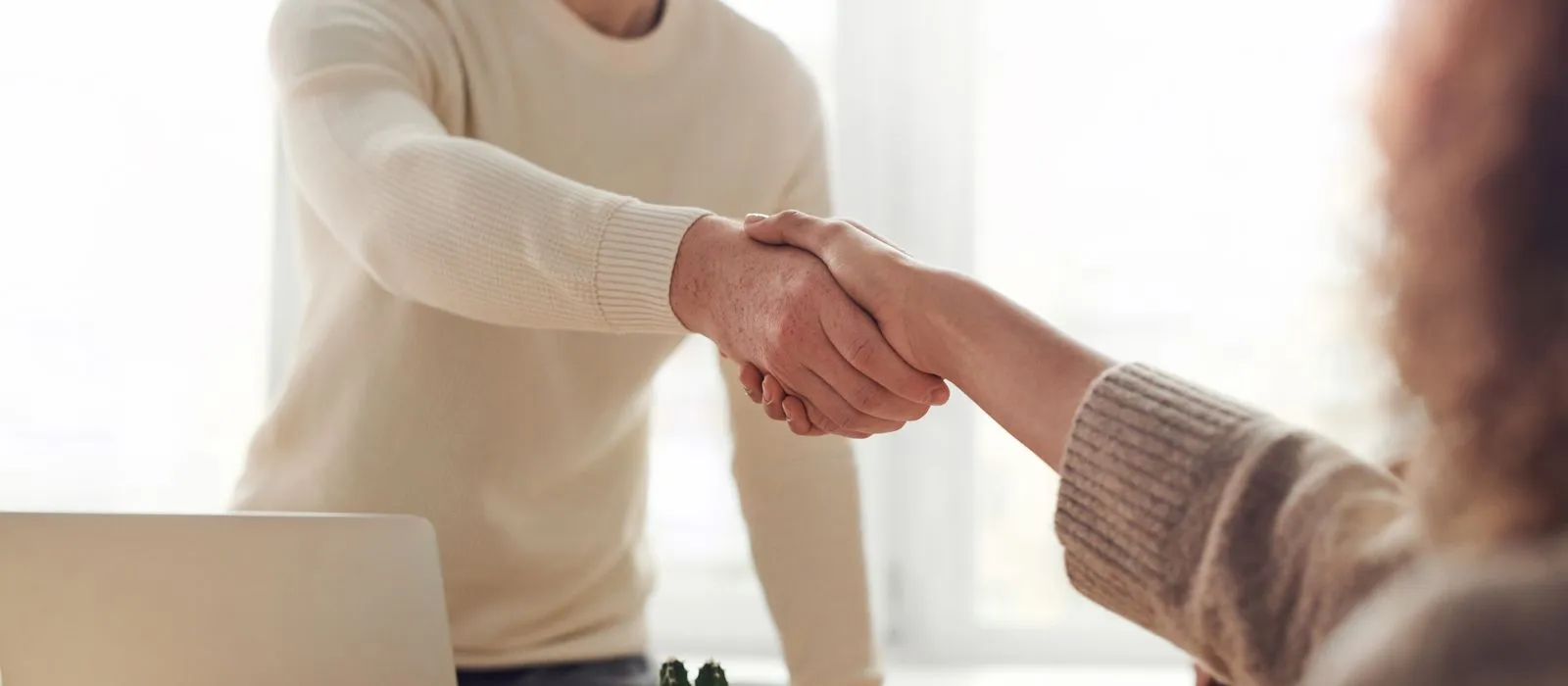 An advisor shaking hands with a client at a desk, financial advisor web design by Designs by Delia