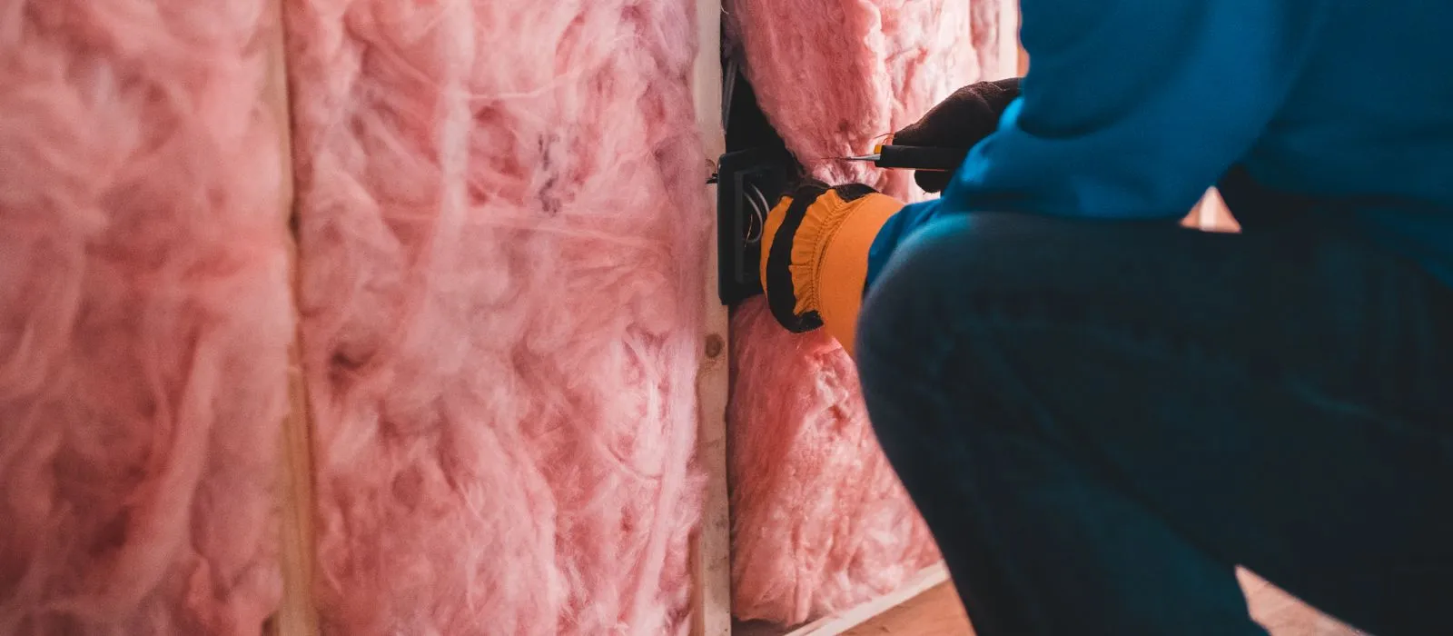 An installer fitting batt insulation between wall studs, insulation contractor web design by Designs by Delia