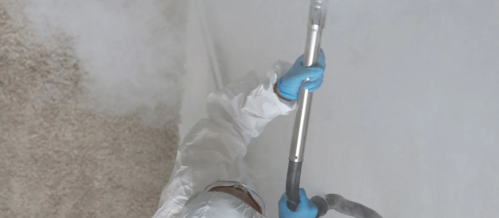 A remediation technician in protective equipment treating an interior wall, mold remediation web design by Designs by Delia