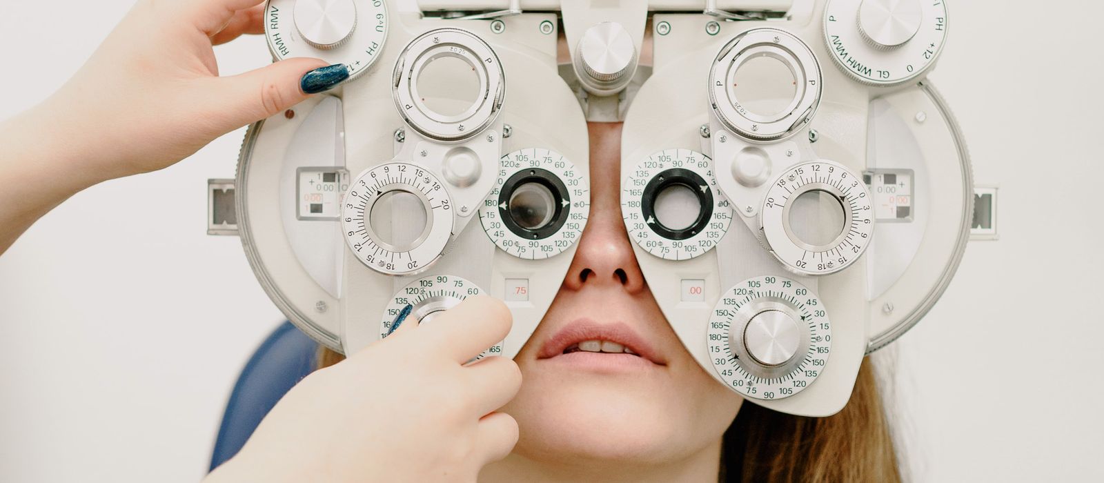 An optometrist performing an eye exam with a phoropter, optometrist web design by Designs by Delia