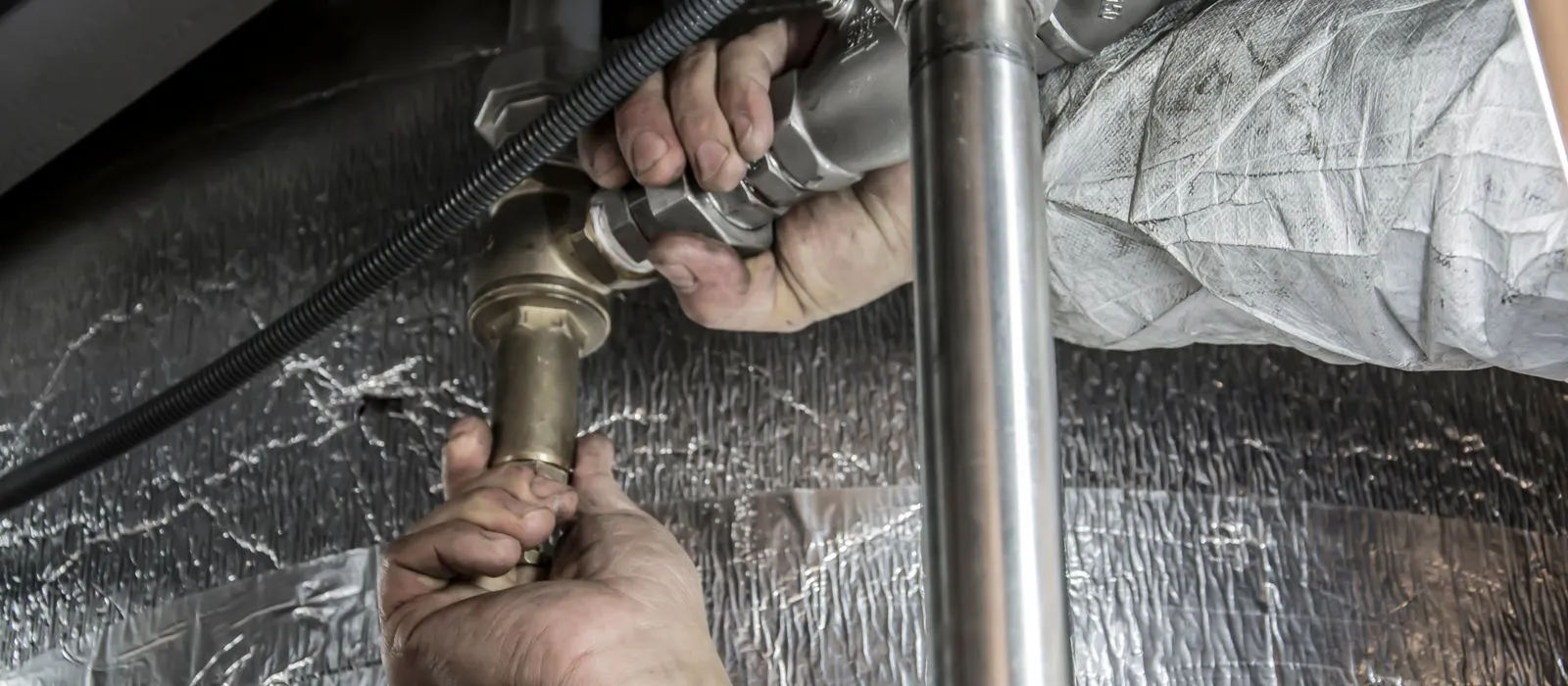A plumber working on pipes, plumbing web design by Designs by Delia
