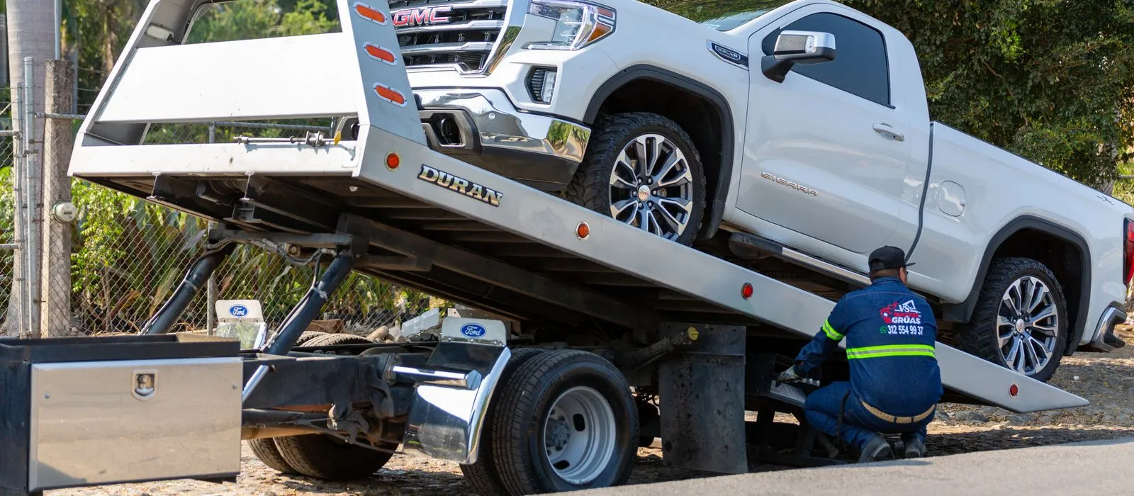A tow truck loading a pickup on a flatbed, towing company web design by Designs by Delia
