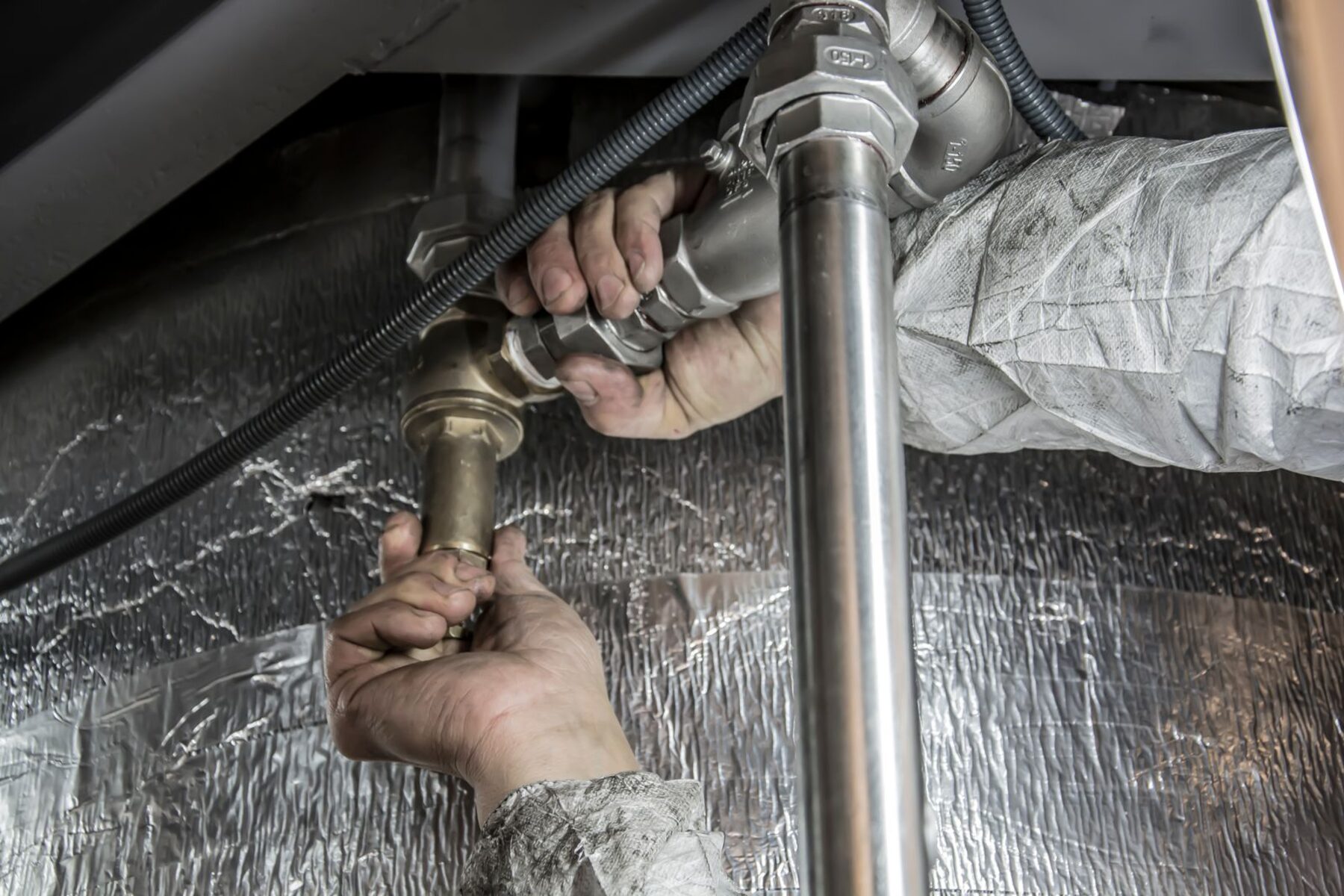 Plumber fitting pipework under a sink