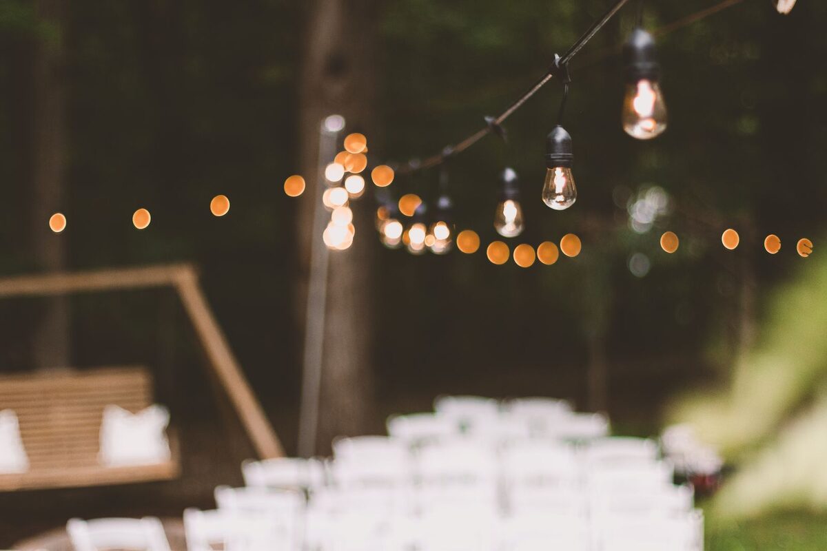 String lights over an outdoor gathering at dusk